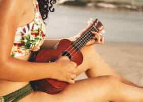 Foto gratuita mujer tocando el ukelele en la playa