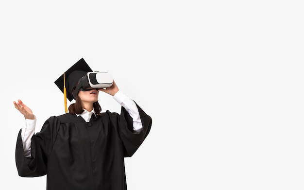 Mujer con toga y gorra de graduación con casco de realidad virtual