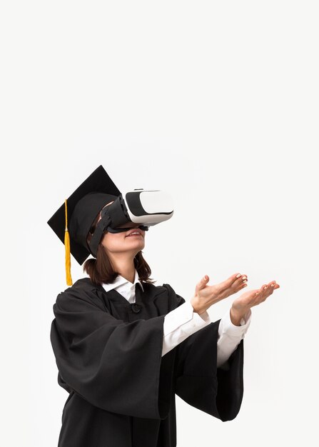 Mujer con toga y gorra de graduación con casco de realidad virtual