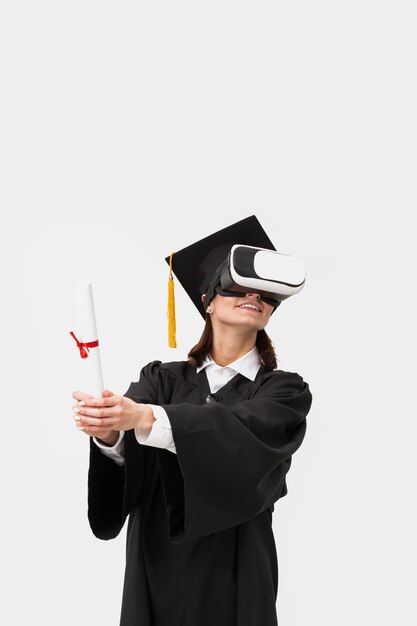 Mujer con toga y gorra de graduación con casco de realidad virtual