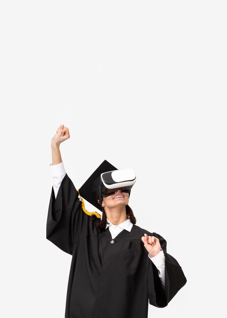 Mujer con toga y gorra de graduación con casco de realidad virtual