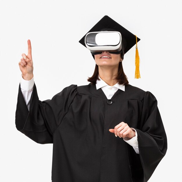 Mujer con toga y gorra de graduación con casco de realidad virtual