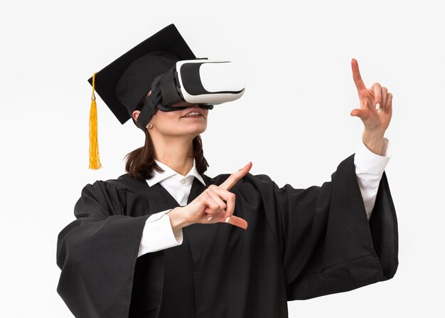 Mujer con toga y gorra de graduación con casco de realidad virtual