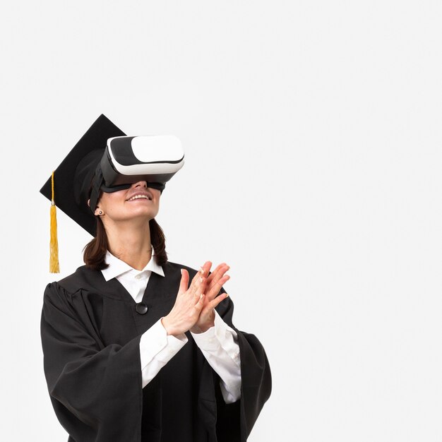 Mujer con toga y gorra de graduación con casco de realidad virtual