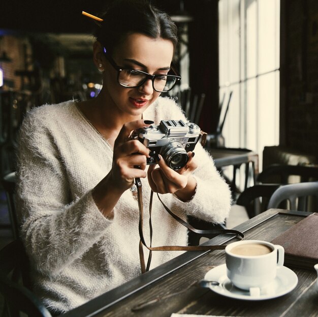 La mujer toma una foto en cámaras fotográficas retros que se sientan en el café