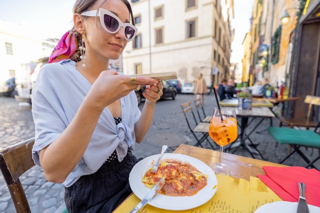 Mujer toma una foto de pasta italiana en un restaurante en la calle en roma