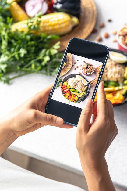 Foto gratuita una mujer toma una foto de un plato de verduras en su teléfono inteligente