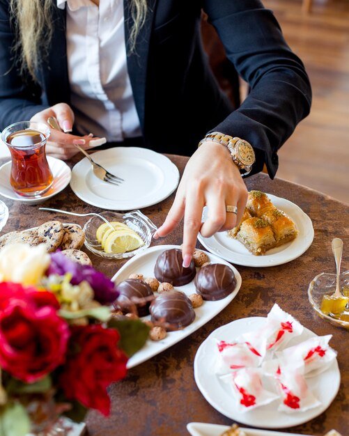 Mujer toma pastel de chocolate para comer con té