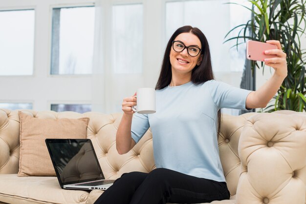 Mujer, toma, selfie, con, café, en, sofá