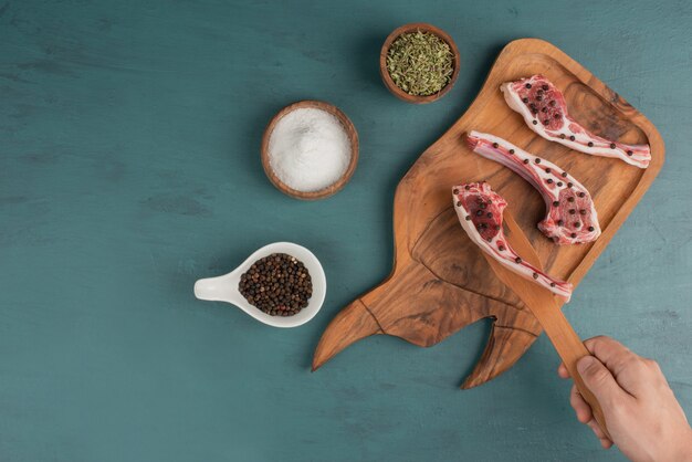 La mujer toma un trozo de carne cruda de la tabla de madera.