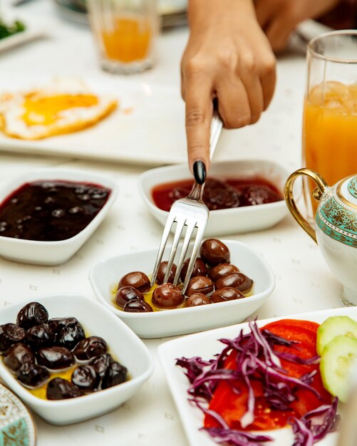 Mujer tomando aceituna negra servida para el desayuno