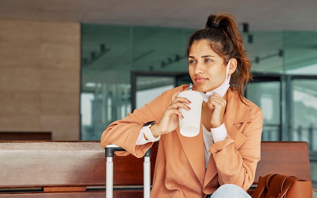 Mujer tomando café en el aeropuerto durante la pandemia