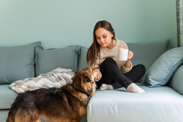 Mujer tomando café en casa con su perro durante la pandemia