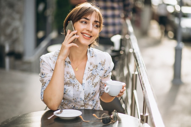 Mujer tomando café y hablando por teléfono