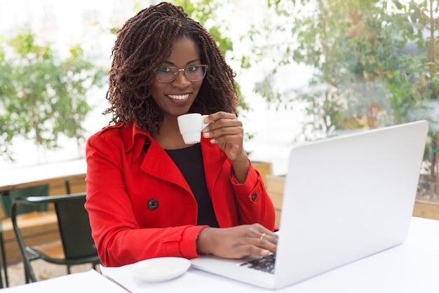 Mujer tomando café y usando laptop