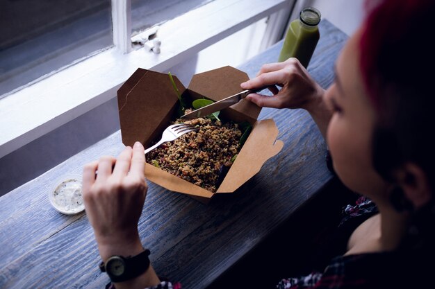 Mujer tomando una ensalada en el café