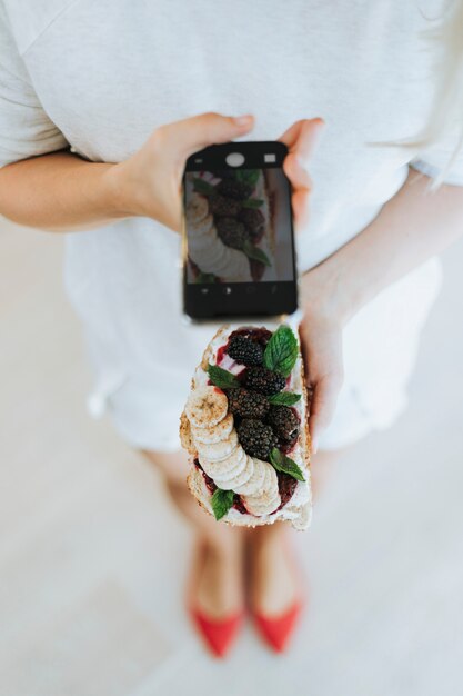 Mujer tomando una foto de un brindis con mermelada de moras y queso crema vegano