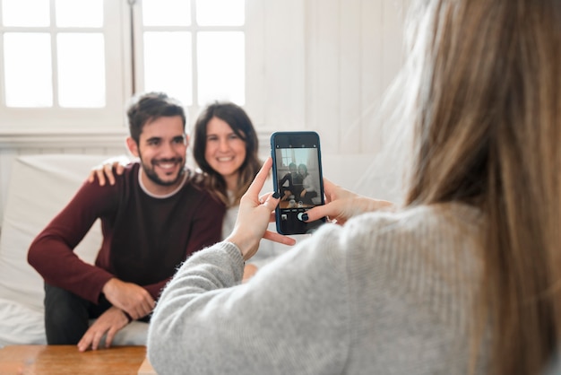 Mujer tomando foto de pareja con teléfono