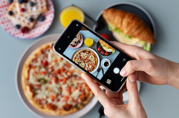 Mujer tomando una foto de una pizza en rodajas y una taza de café