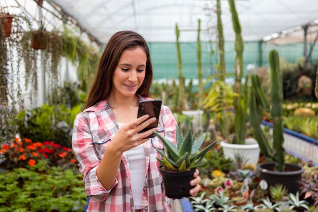 Mujer tomando foto de planta con teléfono