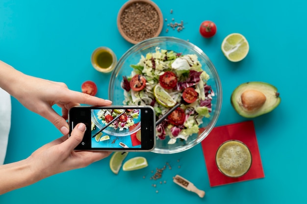 Mujer tomando una foto de un plato con ensalada y un tenedor