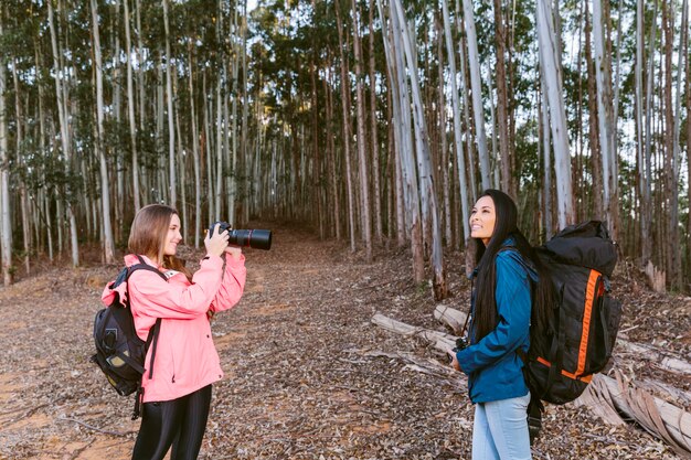 Mujer tomando foto de su amigo en el bosque