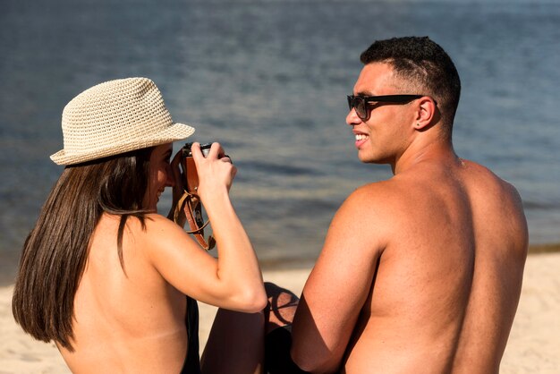 Mujer tomando la foto de su pareja en la playa.