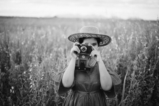 Mujer tomando una fotografía con una cámara antigua en blanco y negro