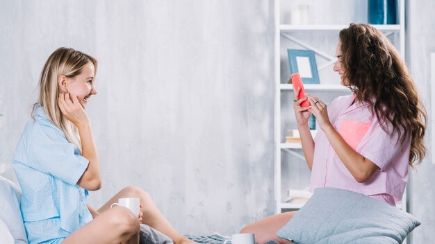 Mujer tomando fotografía de su amigo con teléfono móvil