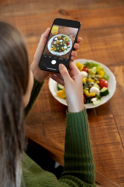 Foto gratuita mujer tomando fotografías de su comida con su smartphone