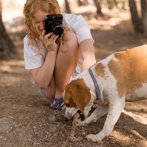 Mujer tomando fotografías de su perro mordiendo un tronco