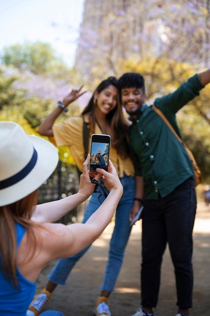 Mujer tomando fotos de amigos vista lateral