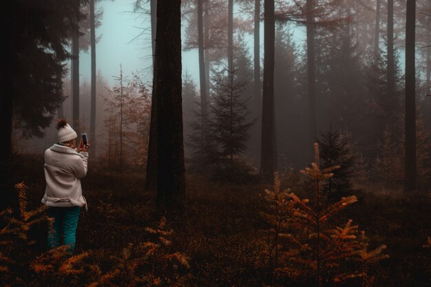 Mujer tomando fotos de árboles en el bosque