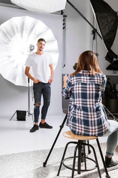 Mujer tomando fotos de hombre guapo en estudio