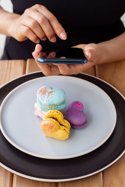 Mujer tomando fotos de macarons en forma de corazón en aviones con teléfono inteligente