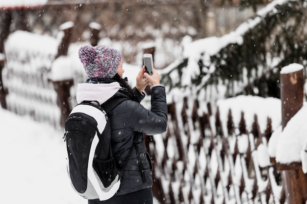 Mujer tomando fotos de la naturaleza de invierno