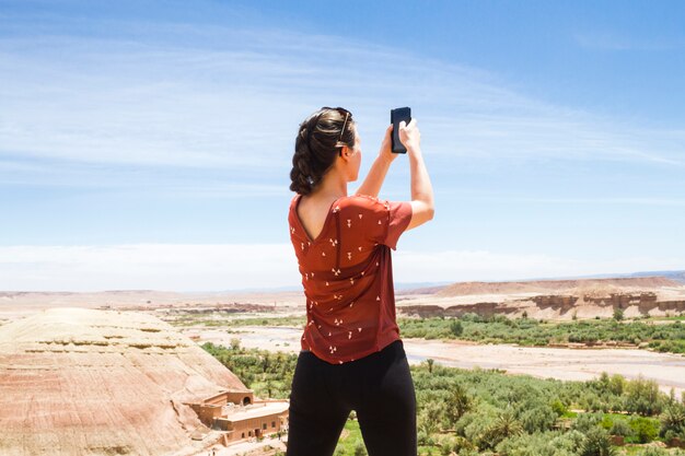 Mujer tomando fotos en paisaje desértico desde atrás