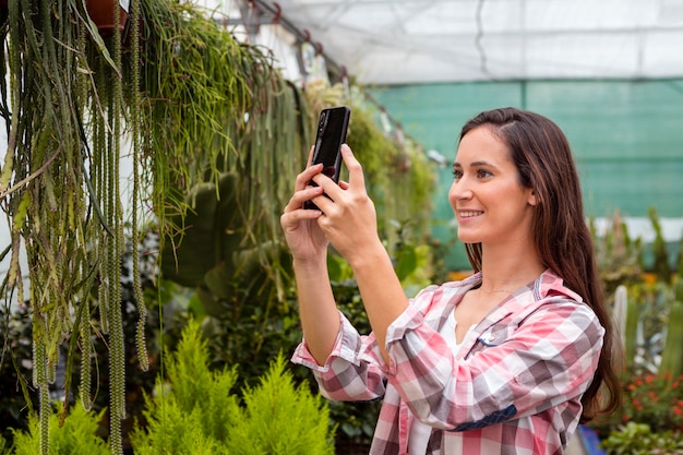 Mujer tomando fotos de plantas en invernadero
