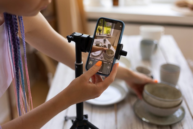 Mujer tomando fotos para su negocio con utensilios de cocina de cerámica