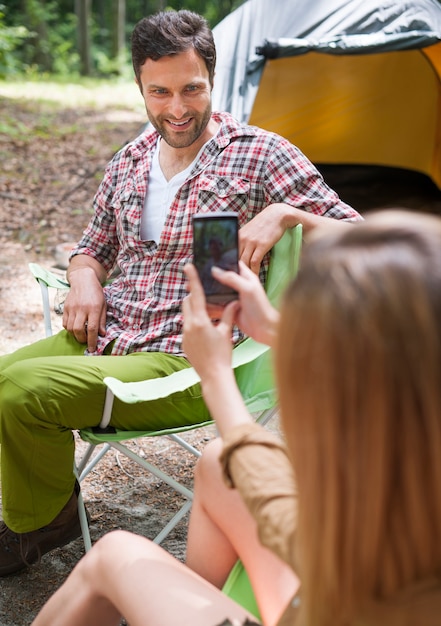 Mujer tomando fotos de su novio en el bosque