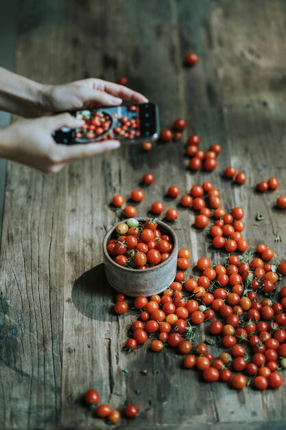 Mujer tomando fotos de tomates cherry rojos