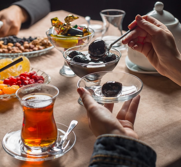 Mujer tomando mermelada de nuez de un recipiente de cristal con soporte en el asiento de té