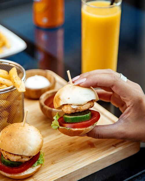 Mujer tomando mini hamburguesa de pollo