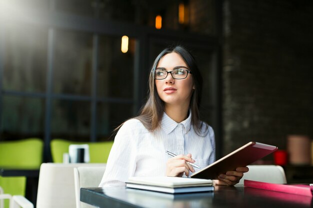 Mujer tomando notas en la cafetería