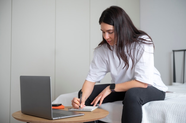 Foto gratuita mujer tomando notas en casa durante la cuarentena