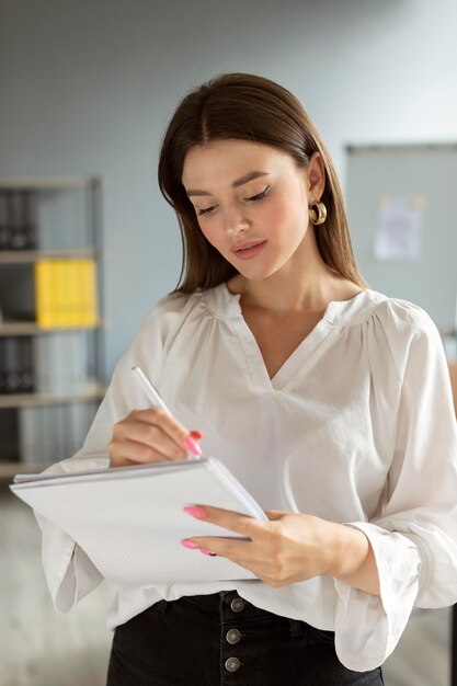 Mujer tomando notas en su cuaderno en el trabajo