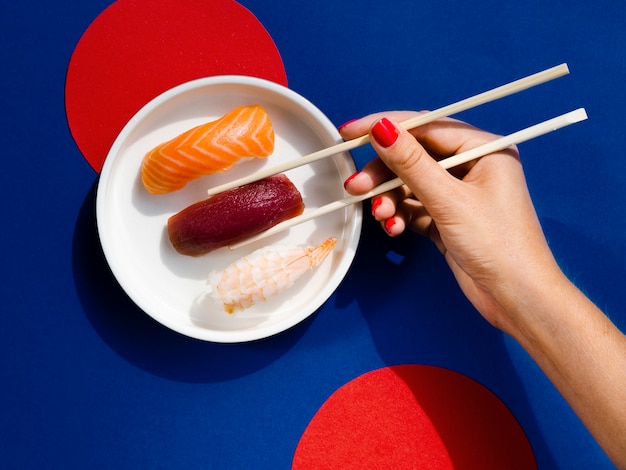 Foto gratuita mujer tomando con palillos un sushi de atún