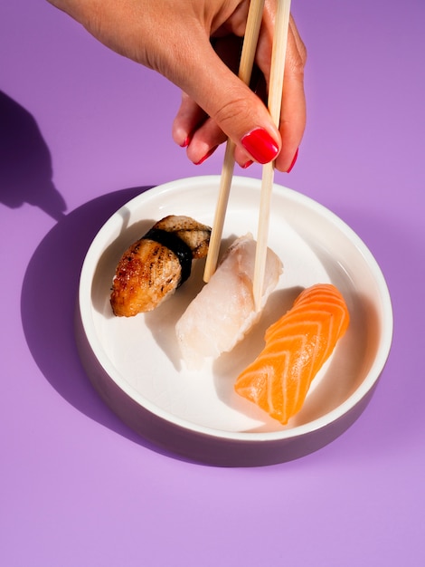 Mujer tomando con palillos sushi de un plato blanco