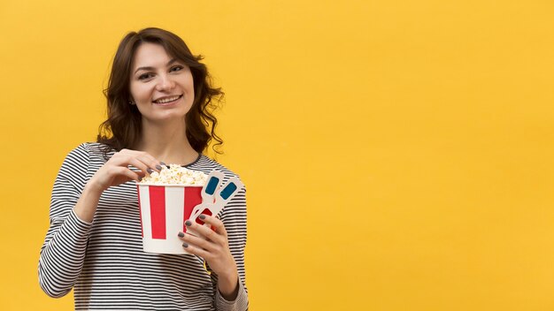 Mujer tomando palomitas de maíz de un cubo con espacio de copia