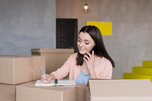 Mujer tomando pedidos desde casa rodeada de cajas